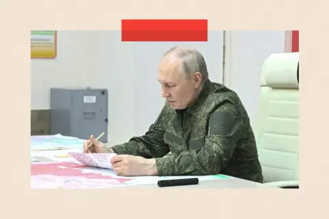 Kremlin Press Office handout via Getty Images A screen grab from a video which shows Russian President Vladimir Putin, dressed in military uniform, with maps and documents in front