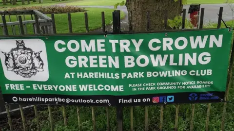 Handout Harehills Bowling Club  banner on a fence