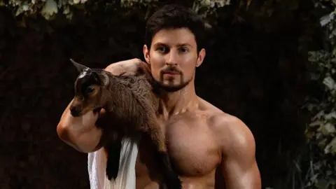 Tech billionaire Pavel Durov poses shirtless with a brown goat on his right shoulder.