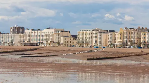Getty Images A row of big white houses are visible in the distance with a beach at low-tied in front. 