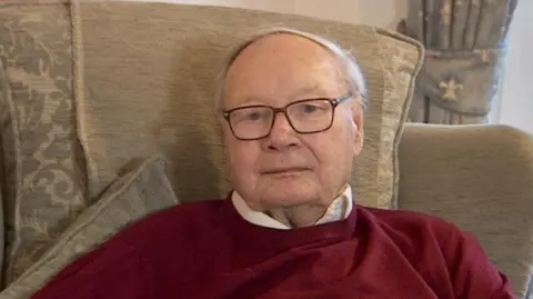 David Baker, pictured in 2021, sat at home, looking at the camera