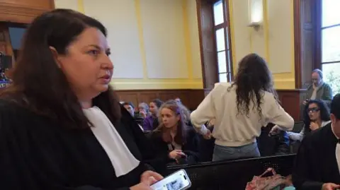 Getty Images A woman in legal clothing attends a trial wearing black and white with black hair