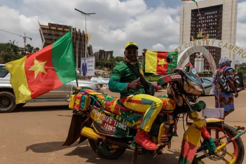 ZOHRA BENSEMRA / REUTERS A man poses for photos on his motorbike. The vehicle and his clothes match the yellow, red and green flag he carries.