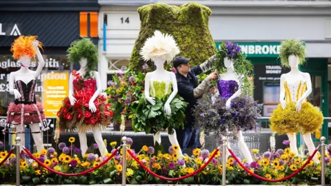 A florist puts the finishing touches to a sculpture of Girls Aloud