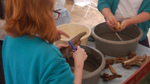 Close-ups of two primary school children washing bones discovered at Rendlesham