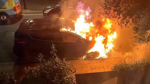 A car on fire during the night.