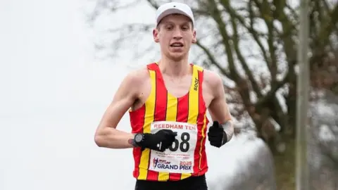 Dreampace A runner is wearing a vest with vertical red and yellow stripes. 