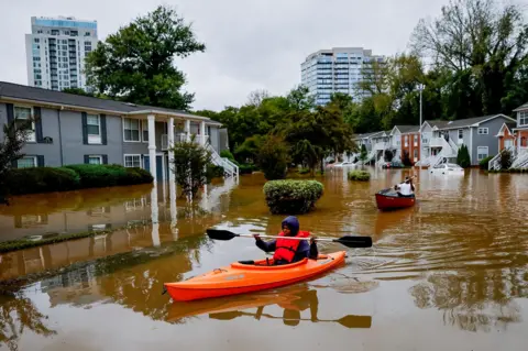 Erik Lesser/EPA-EFE Peachtree Park Apartments resident Candice Ocvil (left) and Jibri Tolenrow through flood waters from Peachtree Creek, Georgia