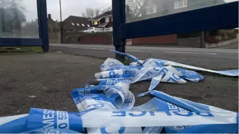 A close up of police tape piled up on the side of a residential road