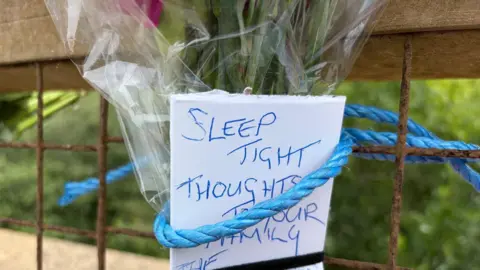 A note which says "sleep tight thoughts with your family" attached to a bunch of flowers with blue rope.