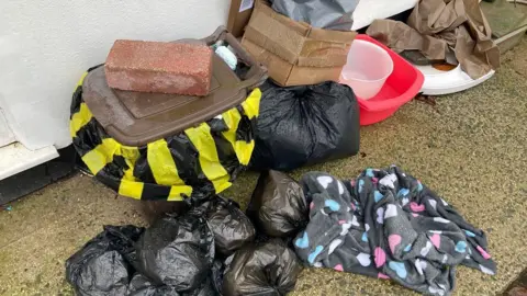 Bags, bins and dirty clothing pilled up outside their house