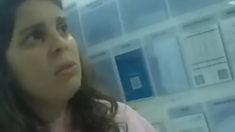 Merseyside Police Police bodycam footage showing Nivalda Pirjani, who has brown hair and is wearing a pink jumper. She has a concerned expression as she looks towards a police officer who is out of vision.