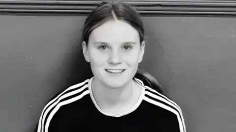 Family handout A black and white photograph of Holly Newton who is wearing a black top with white piping. She has her hair tied back and is smiling.