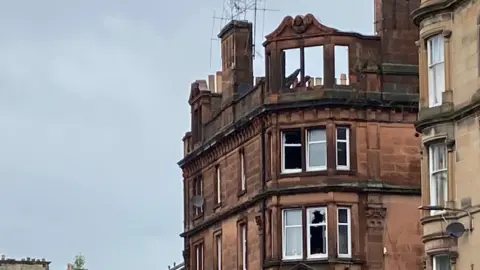 A tenement block in Perth which has been badly damaged by fire. the roof and upper windows have collapsed and several other windows are smashed.