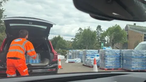 A Thames Water worker hauls bottled water out of a car.