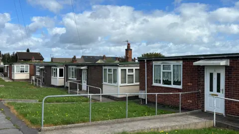 A row of bungalows with grass in front of them.