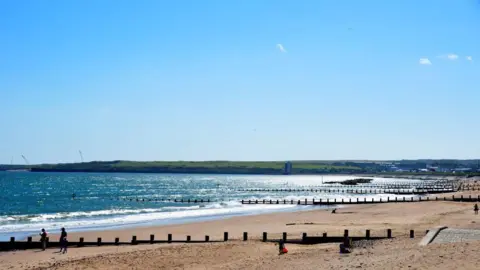 Getty Images Sandy beach with wooden spines, blue sea and blue sky, in Aberdeen