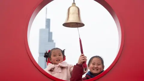 Two young girls ring the New Year bell on the city wall of Nanjing on the first day of the Chinese Lunar New Year in Nanjing, China, on February 17, 2026.