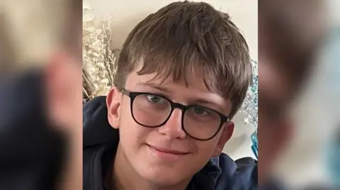 Family Handout A young boy with black glasses smiles at the camera