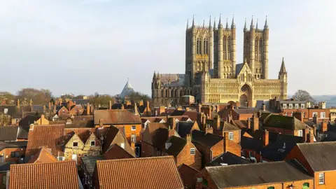 View of Lincoln Cathedral taken from the nearby castle walls. There are red-bricked houses in the foreground.