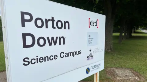 A sign which has Porton Down written on it in black writing on a white background