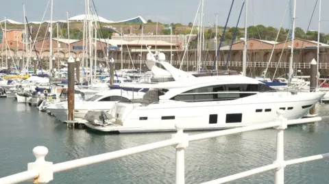 Yachts in a marina in Jersey. Most of the boats are white.