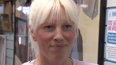 A head and shoulders view of cafe owner Willow Boyle, who has blonde hair and wears a pink t-shirt.