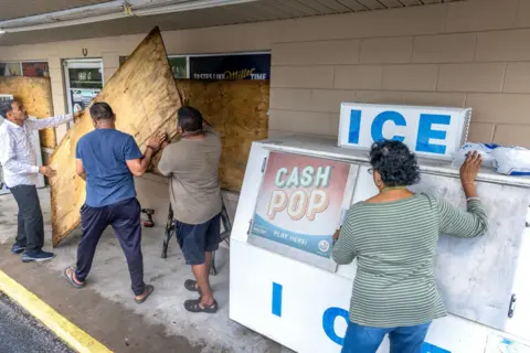  Cristóbal Herrera/EPA-EFE People cover windows with plywood as the town prepares for Hurricane Helene in Mayo, Florida