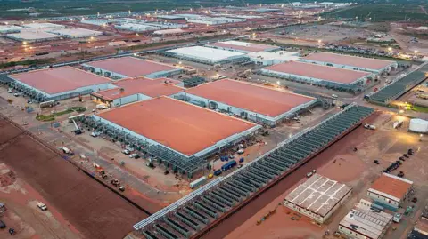 Getty Images An aerial view of several large flat, rectangular buildings with reddish brown roofs showing a large date centre in Texas under construction.