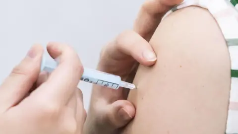 Close up shot of arm with a hand administering a vaccine.