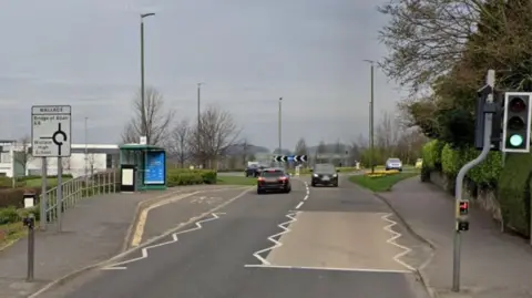 Google A stretch of road with a roundabout in the far distance and zig-zag lines on the road.