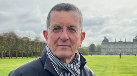 Sir Antony Gormley has short greyish black hair and is wearing rounded glasses.