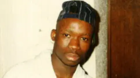 A close up photo of James, who is looking into the camera and wearing a cap.