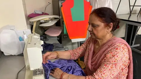 Paramjit Kaur seduto accanto a una macchina da cucire