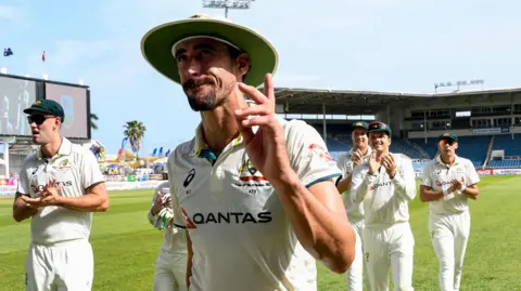 Australia quick bowler Mitchell Starc waves as he walks off, applauded by his team-mates