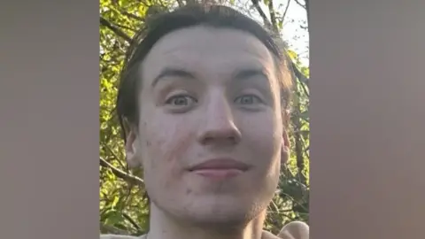 A close-up image of Finbar Sullivan's face. He is a young, slender man with dark hair. 