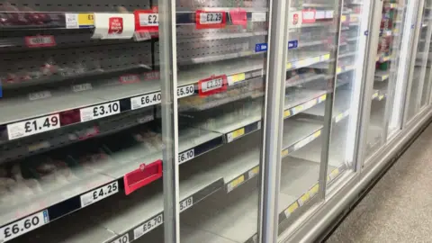 A row of empty fridges in a supermarket