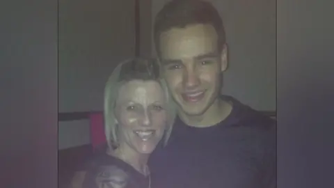 Kerri Dunn Kerri has blonde short hair and is wearing a black top. She is smiling with Liam Payne who has short brown hair and a black long sleeved top