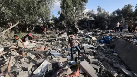 Getty Images Palestinians assess the damage in the aftermath of an overnight Israeli strike that hit Nuseirat in the central Gaza Strip