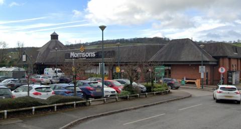 A Morrisons supermarket and car park with cars driving in to park