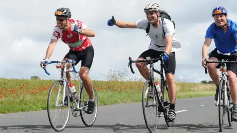 Sarcoma UK Ed Talbot (left) Charlie Hunt (centre) and James Hall-Smith (right) all on cycles in their cycling gear.