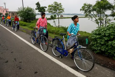 AP Village-meisjes lopen met fietsen die ze van hun school hebben gekregen als onderdeel van een overheidsprogramma in Malancha, district South 24 Pargana, India, 