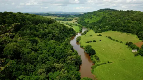 The River Wye, seen from Symonds Yat Rock in Symonds Yat, Herefordshire, near the border with Gloucestershire and Monmouthshire, Wales. On the left is Huntsham Hill, and Coppet Hill is on the right, with the village of Goodrich just visible in the background.