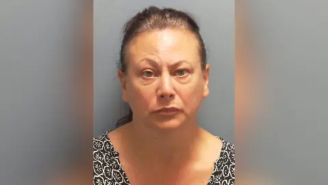 A mugshot of a woman with brunette hair 