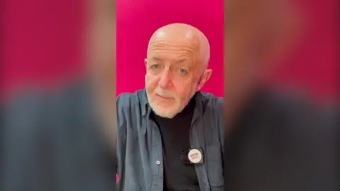Jeremy Bowen in front of a pink background