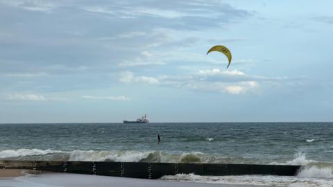 TUESDAY - A kite surfer enjoys a windy day at Southbourne with a larger ship on the horizon