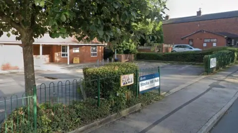 An exterior general view image of a red brick medical centre and car park
