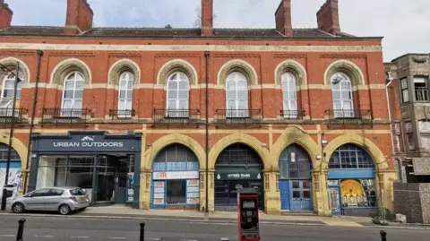 Burslem Market is pictured which is built with agleam  orangish  bricks and windows, connected  a gradient with newer shops underneath it successful  an arch design.