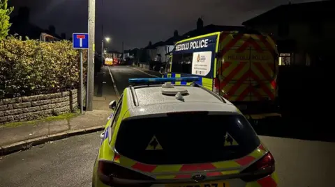 BBC Police cars at the end of a dark street 