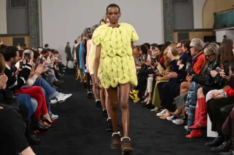 Getty Images Model at London fashion week wearing yellow skirt and top with brown boots